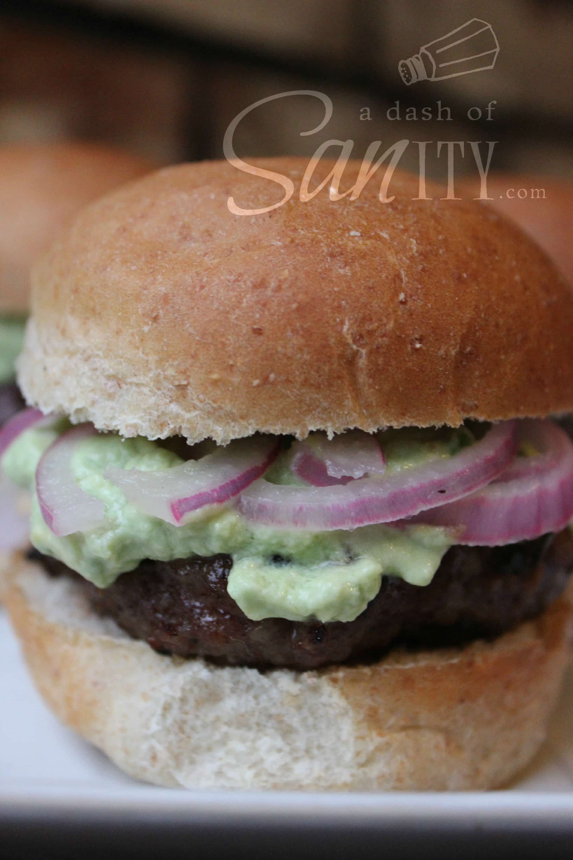 Poblano Slider up close served on a plate with burger, poblano sauce, and sliced red onions