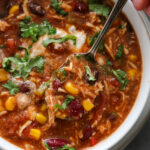 overview shot of chicken chili with spoon and cilantro