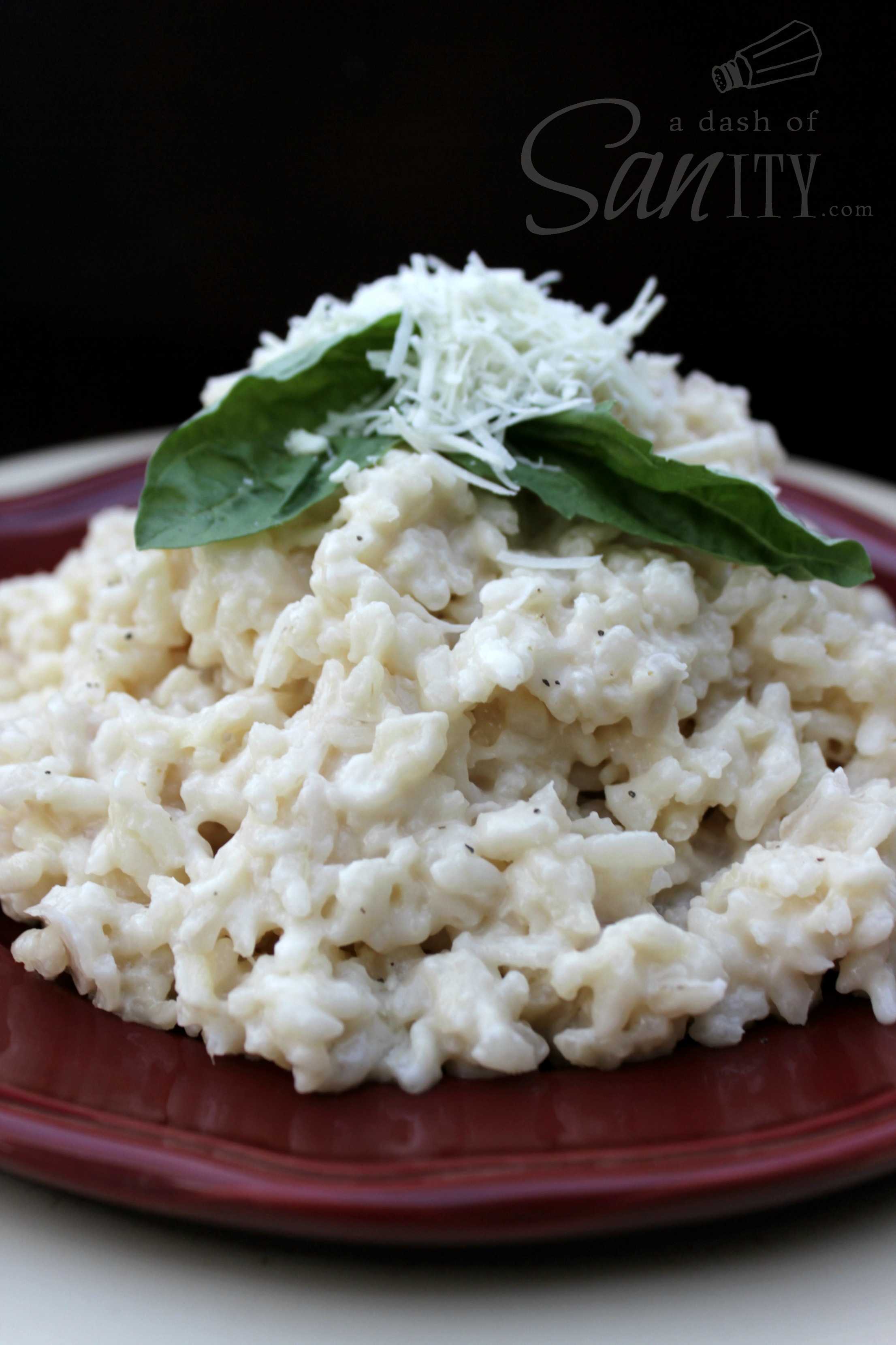 Three Cheese Risotto served on  plate with 2 basil leaves and fresh grated parmesan cheese