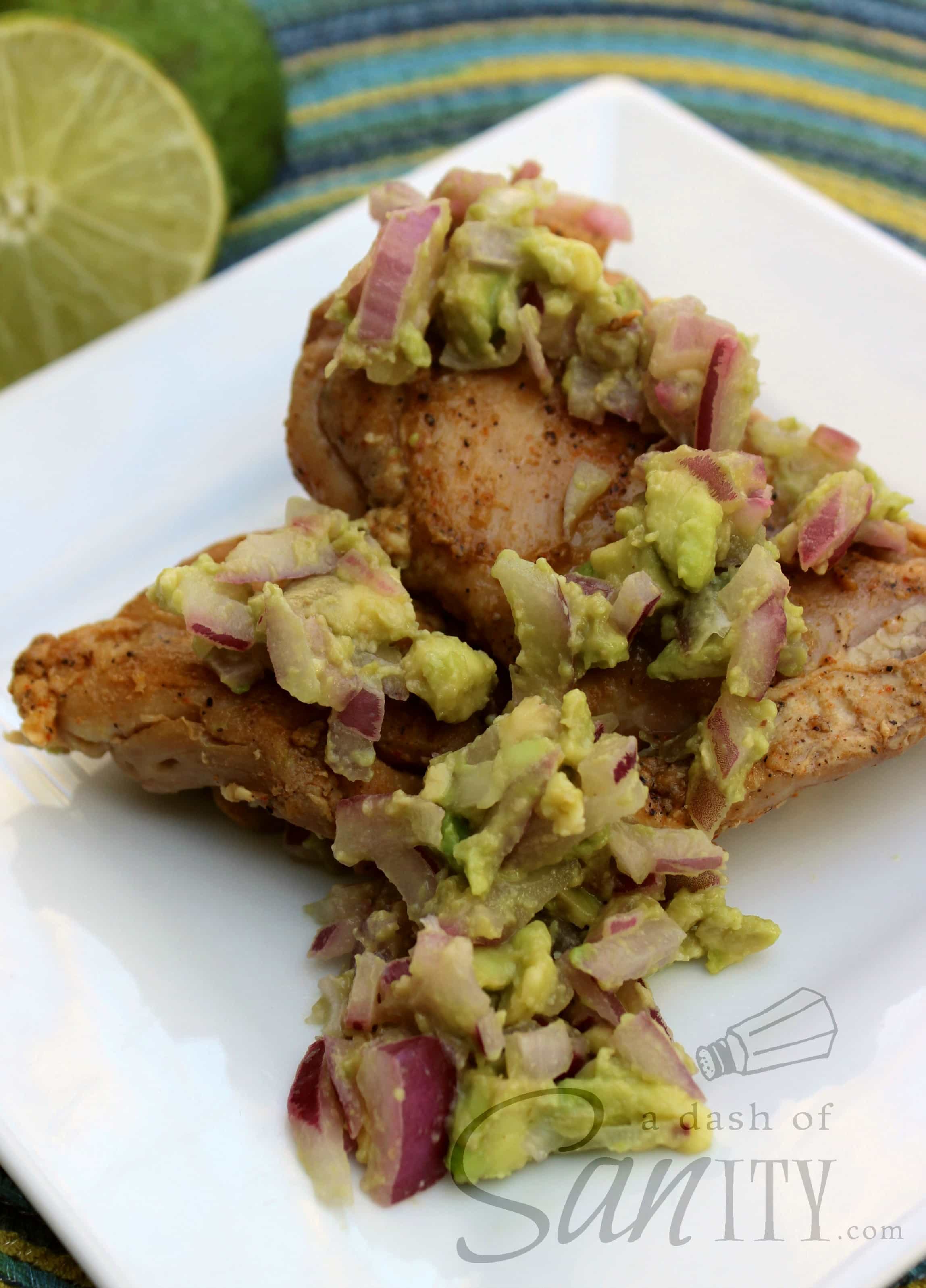 Cayenne Spiced Rubbed Chicken with Avocado Salsa served on a square plate with sliced lime in the background
