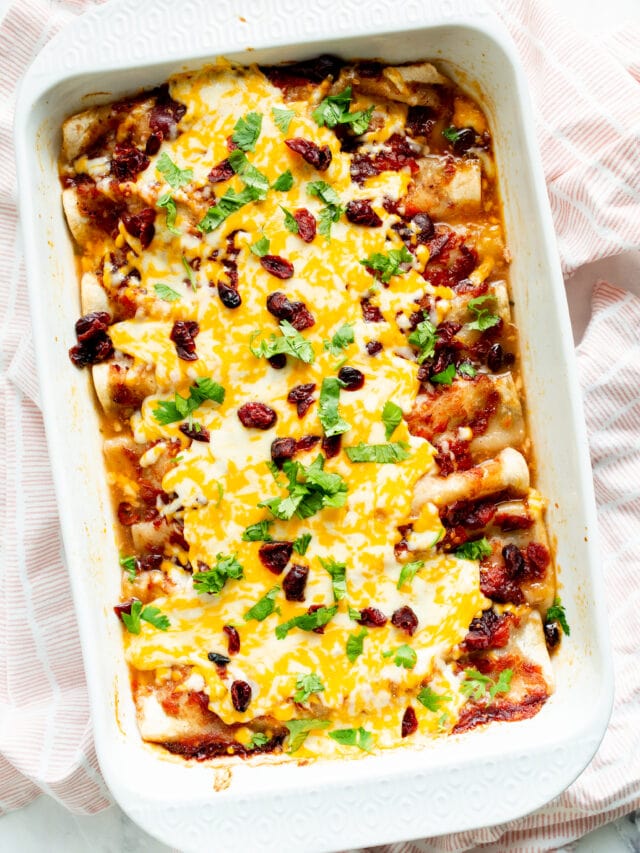 Baked enchiladas with toppings in baking dish viewed from above