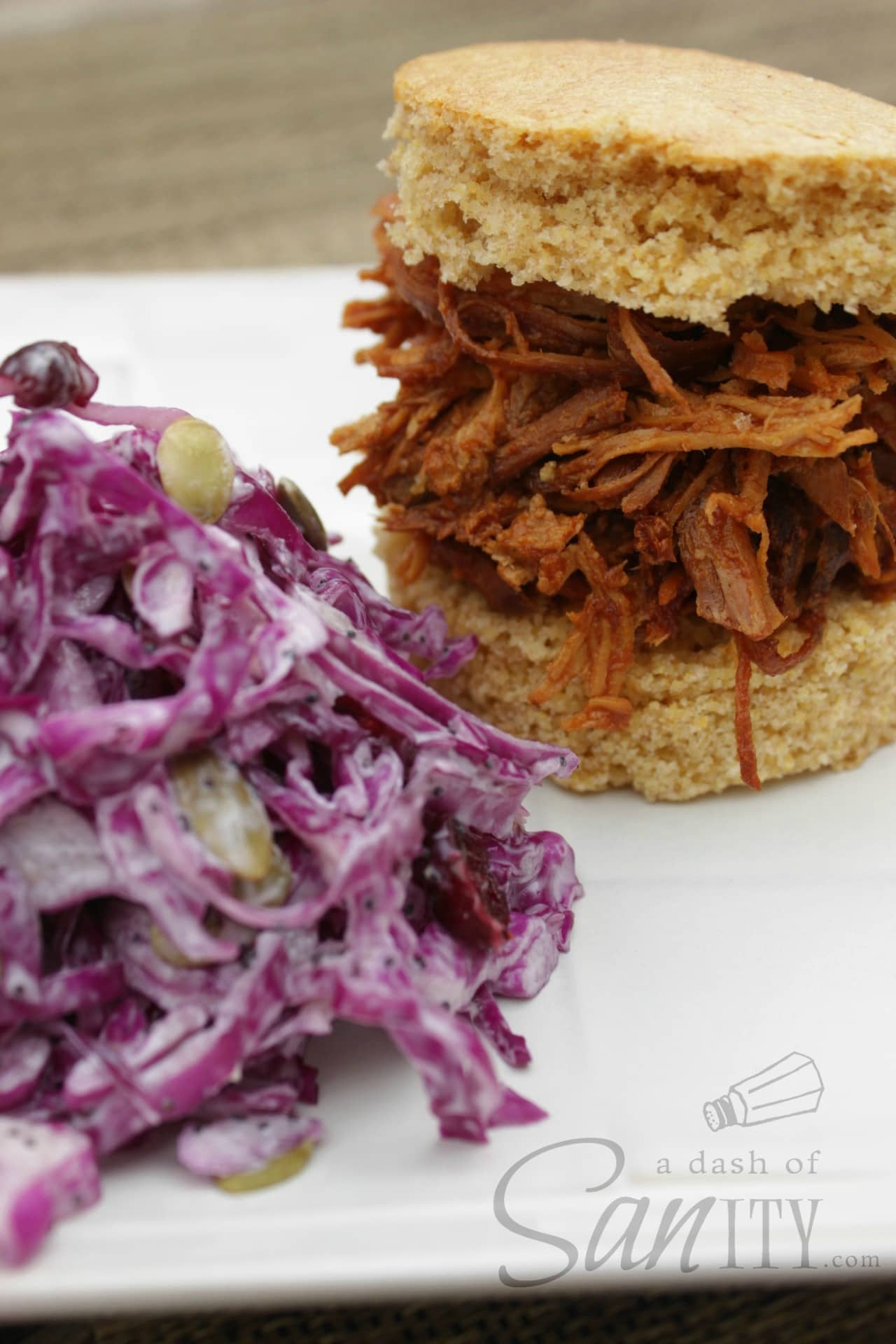 Barbeque Chicken served on sliced cornbread bun on a plate with a serving of Healthy Cole Slaw