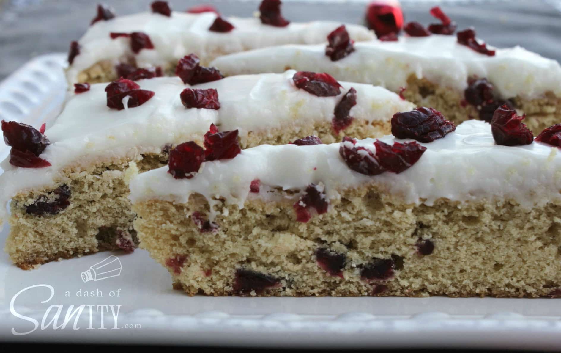 Blissful Cranberry Bars topped with dried cranberries and icing on a plate