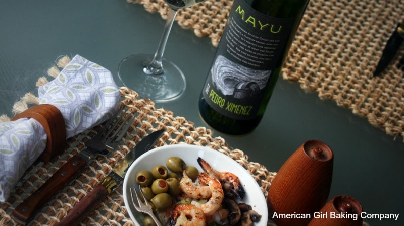 Piquant Grilled Shrimp with Chimichurri Seasoning and green olives served in a bowl with a table setting, with mayu bottle and wine glass