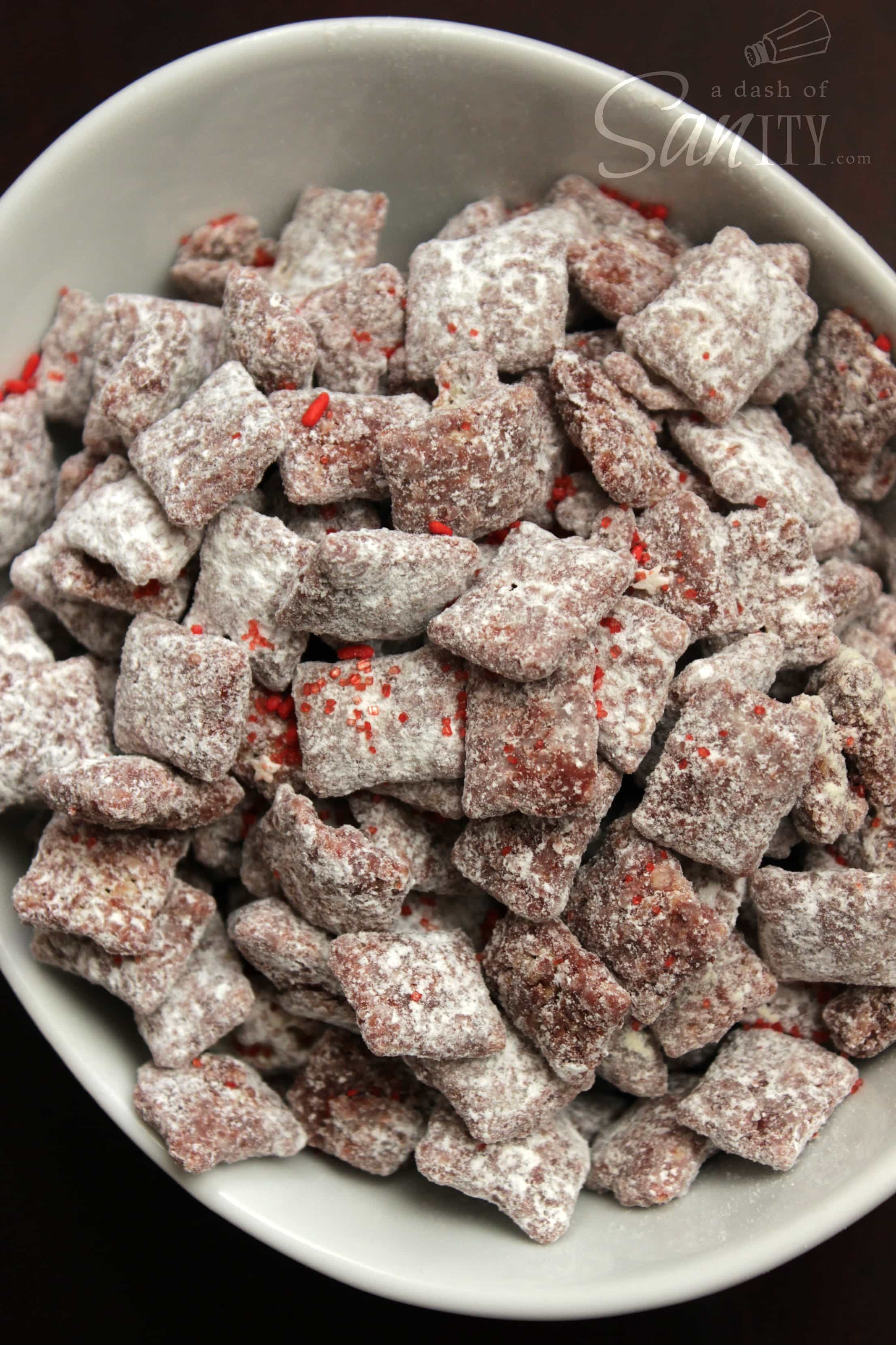 These Chocolate Cherry Cordial Muddy Buddies are a delicious cherry flavored treat. A twist on classic muddy buddies that a perfect for the holidays. Chocolate Cherry Cordial Muddy Buddies in an oval bowl