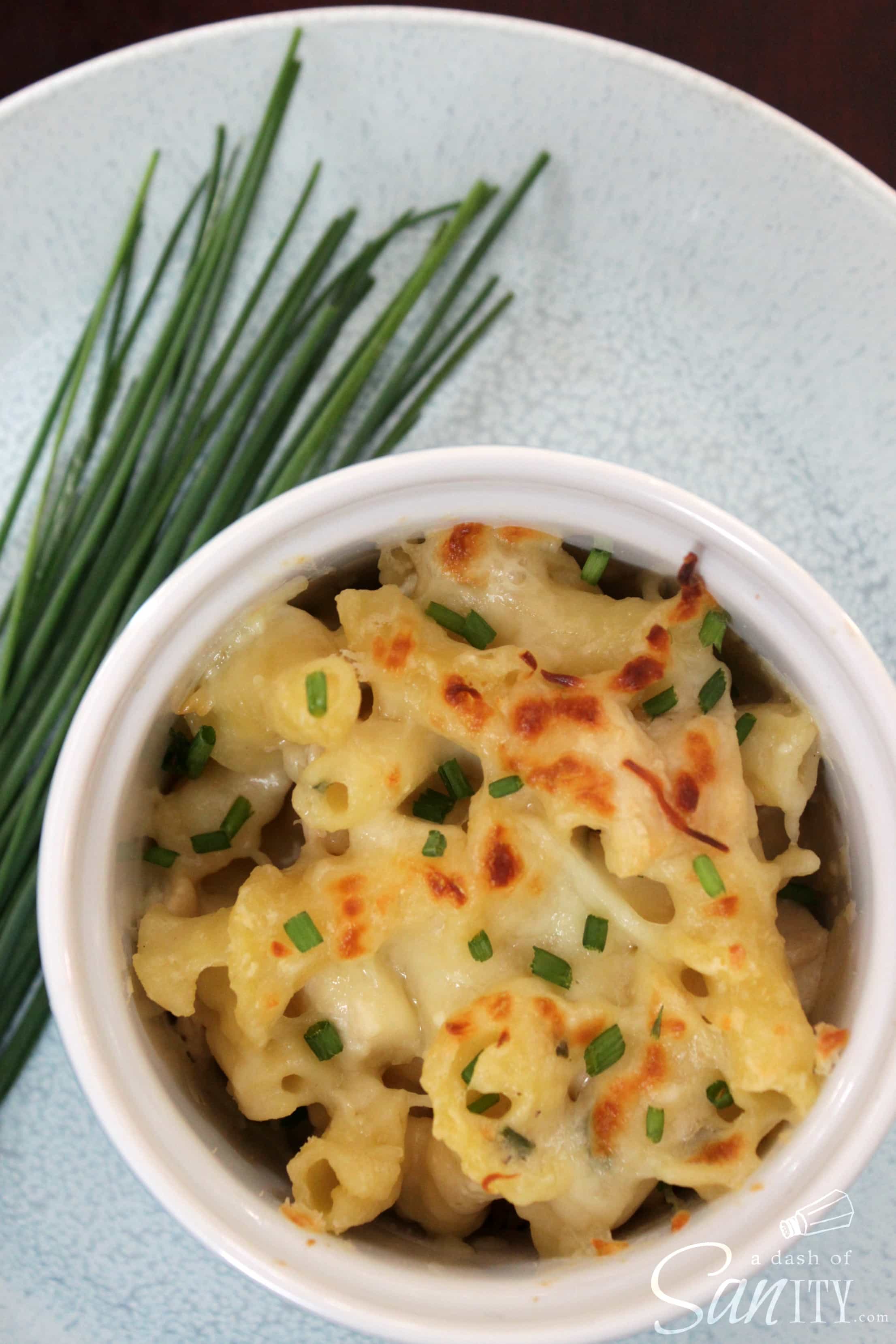 Chive & Garlic Chicken Creamy Pasta Bake in serving bowl with a plate of chives
