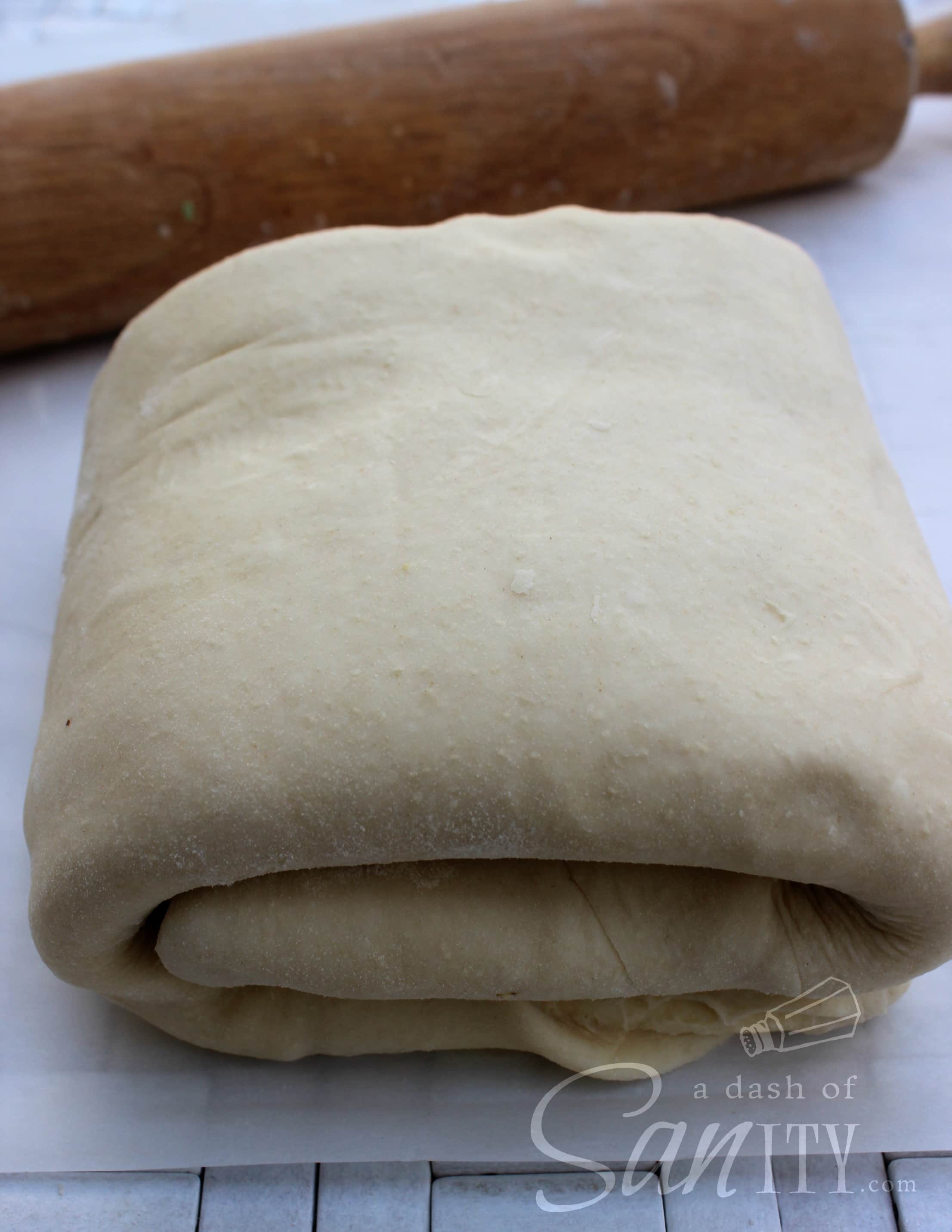 These Chocolate Croissants are light, flaky, buttery croissants with a deliciously rich dark chocolate center. A perfect treat for any chocolate lover. croissant dough folded into a square on parchment paper