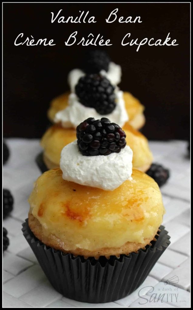 Vanilla Bean Crème Brûlée Cupcakes up close on a counter. cupcake topped with whipped cream and a blackberry