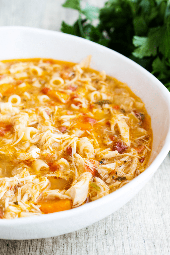 photo of Sicilian Chicken Soup in a white bowl with herbs in background