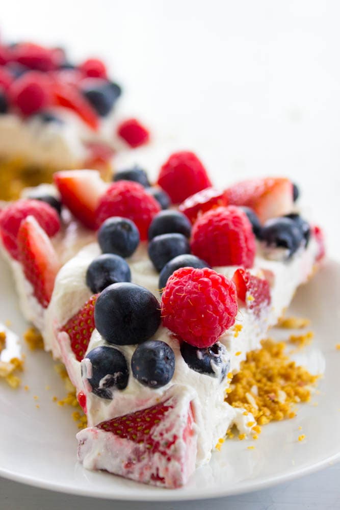 Insanely delicious & easy this Simple No-Bake Fruit Tart is made with an almond graham cracker crust, cream cheese filling, then topped with fresh fruit. photo of a slice of no bake fruit tart on a white plate