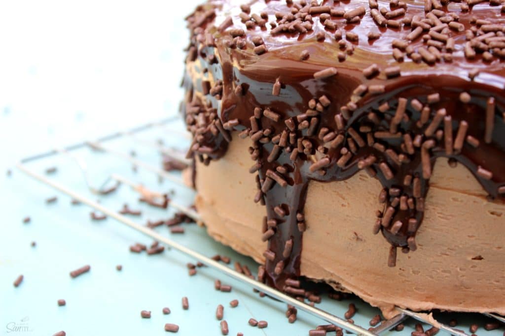 Banana Split Cake is a rich banana cake layered with chocolate, pineapple, and strawberry buttercream that is topped with ganache, cherries, and sprinkles. double chocolate nutella layer cake view