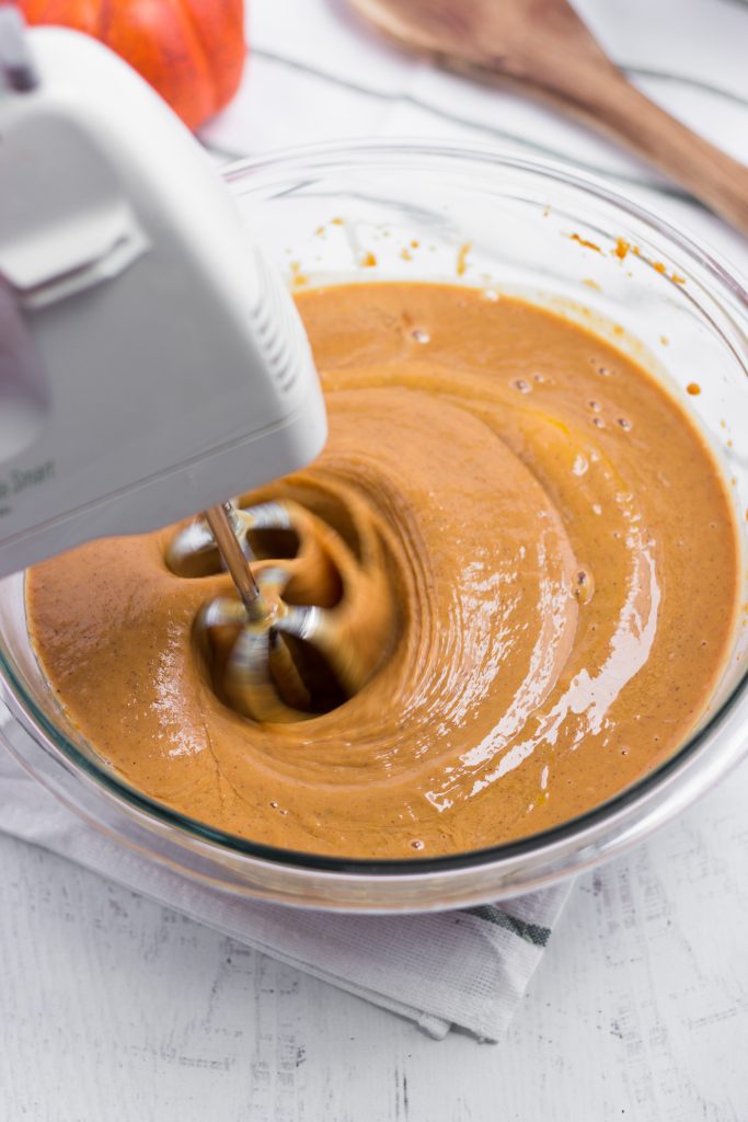 Pumpkin Crisp Pie filling in glass bowl being mixed with a hand mixer