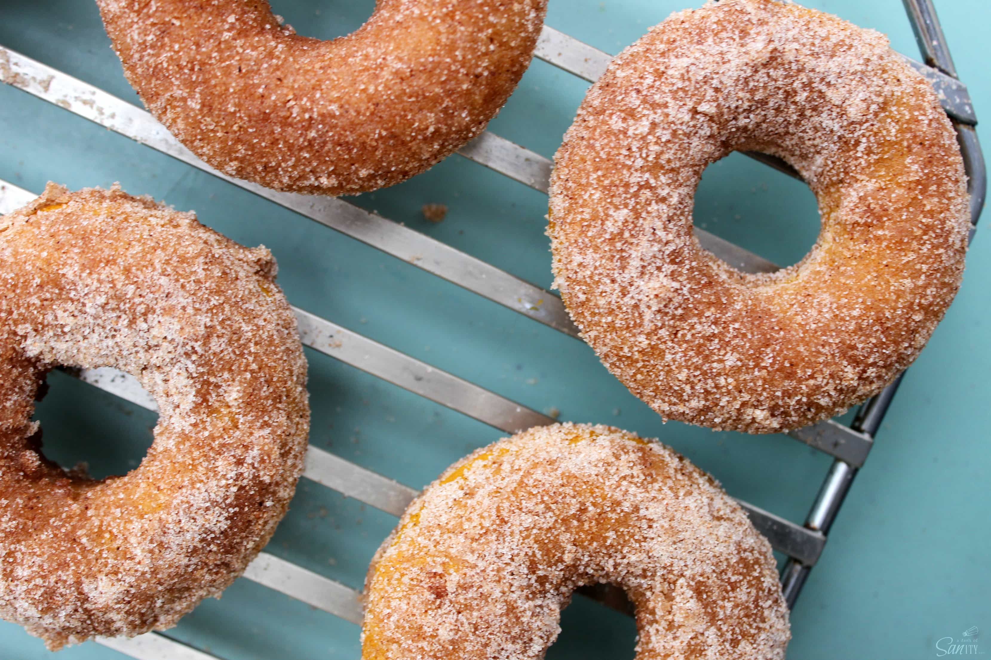 overhead photo of cinnamon sugar pumpkin donuts on cooling rack