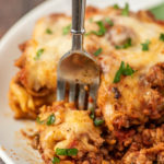 close-up photo of a fork cutting off a bite of lasagna
