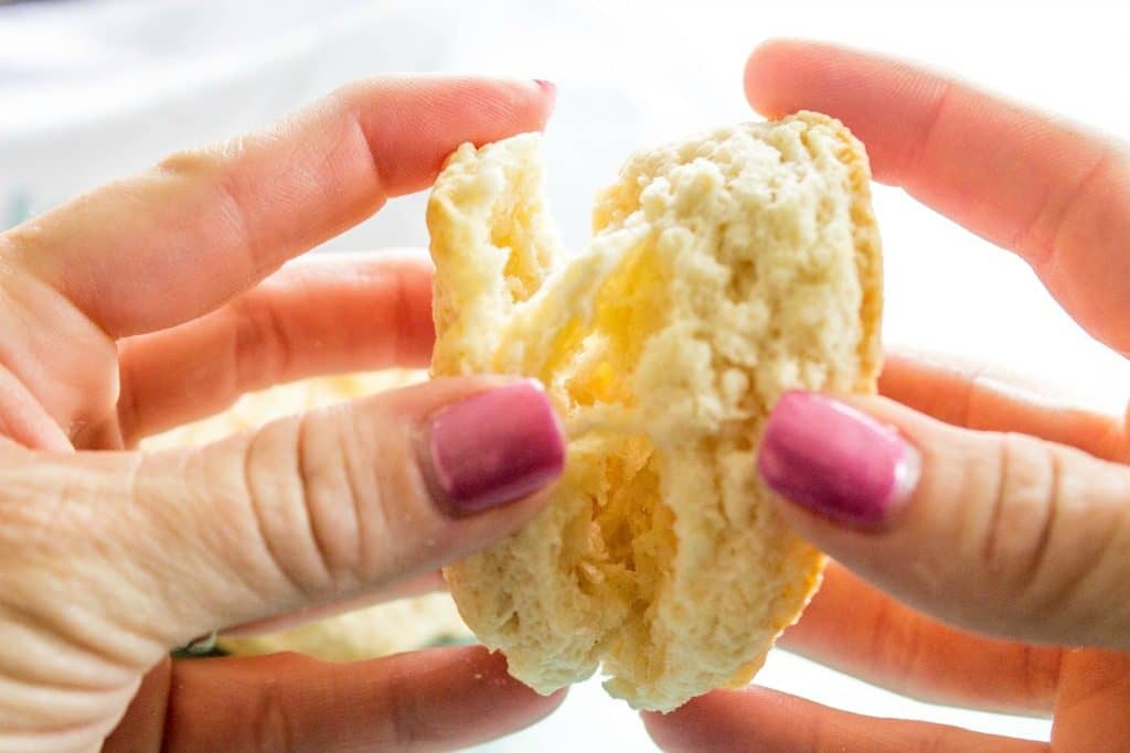 Ready minutes these COPYCAT KFC BISCUITS are light and flaky with layers of buttery dough, you will love these with jam, gravy or more butter. photo showing hands pulling apart a biscuit, with flakey layers inside