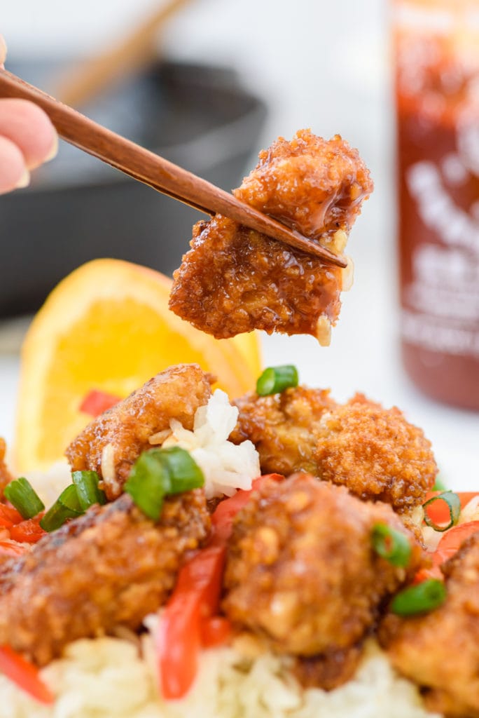 photo of chopsticks holding a piece of chicken