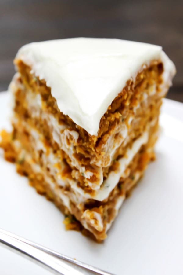 Absolutely dreamy this PUMPKIN ZUCCHINI CAKE is covered in cream cheese frosting, creating the perfect combination for the most delicious cake. a slice of frosted zucchini pumpkin cake on a plate.