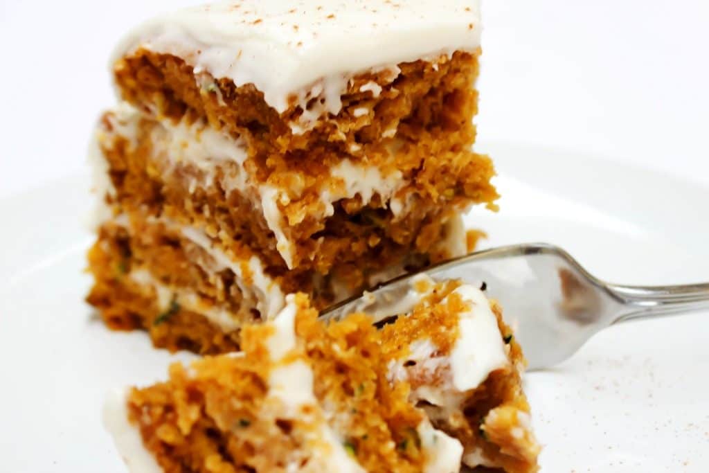 Absolutely dreamy this PUMPKIN ZUCCHINI CAKE is covered in cream cheese frosting, creating the perfect combination for the most delicious cake. a fork and a slice of cake.