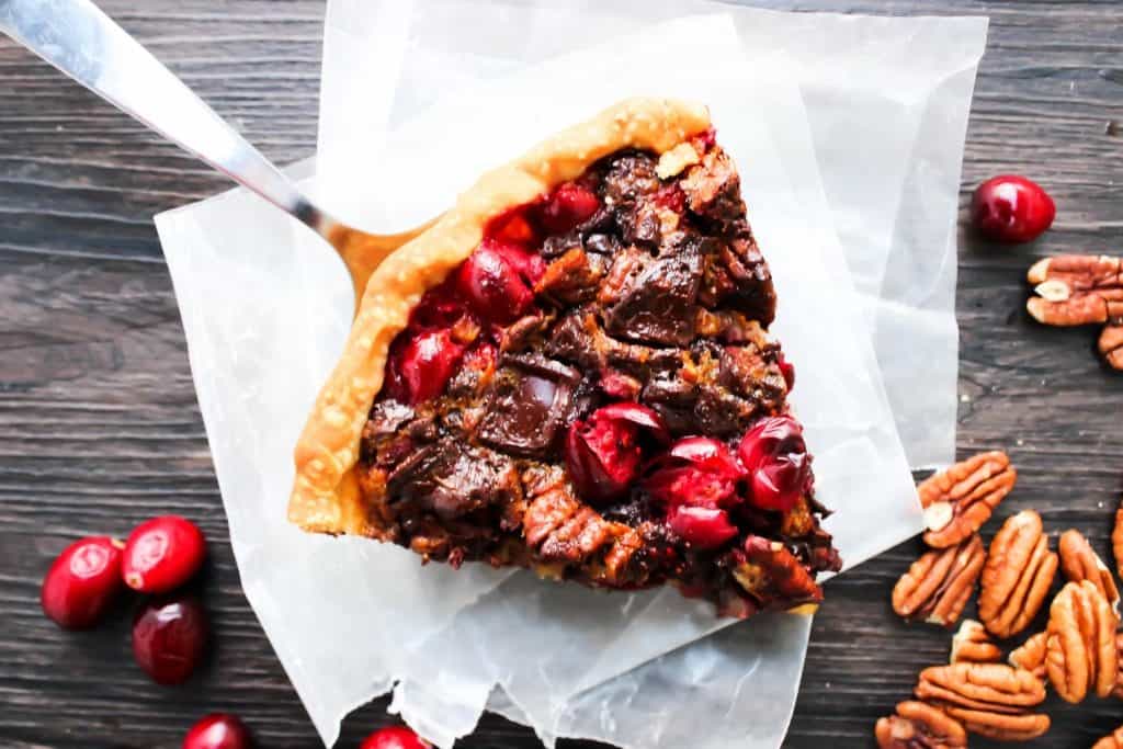 Chocolate Pecan Cranberry Pie a sweet addition to your dessert table. Made with pecans & cranberries it has traditional holiday flavors but with a twist. Chocolate Pecan Cranberry Pie slice