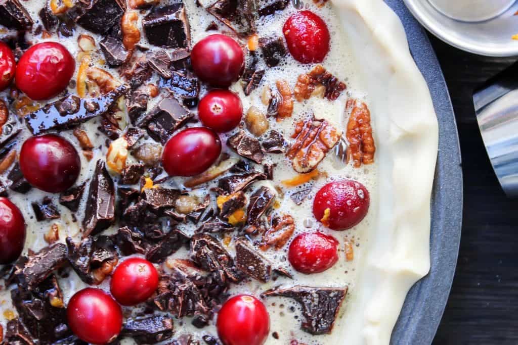 Chocolate Pecan Cranberry Pie a sweet addition to your dessert table. Made with pecans & cranberries it has traditional holiday flavors but with a twist. Chocolate Pecan Cranberry Pie