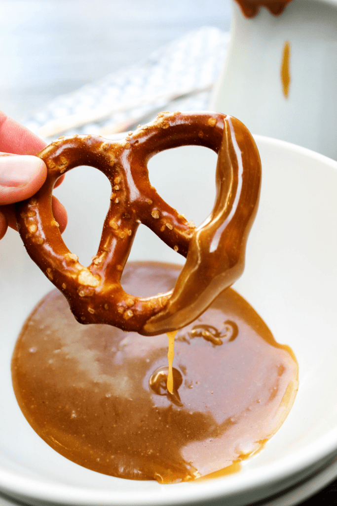 Friends, you’re only ten minutes from peanut butter and caramel euphoria. Ten minutes is all is takes to make this PEANUT BUTTER CARAMEL SAUCE! hard pretzel being dipped into a bowl of Peanut Butter Caramel Sauce