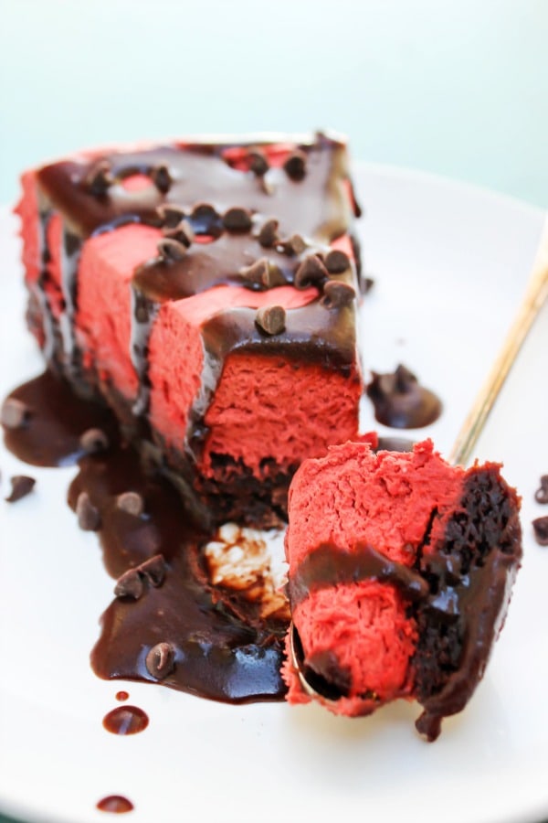 slice of red velvet cheesecake with hot fudge with bite out of it