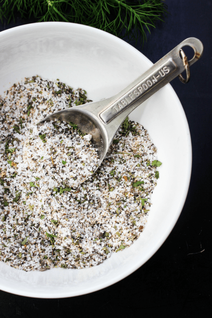 overhead shot of chicken seasoning in while bowl with measuring spoon