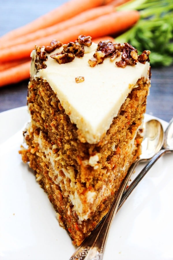 Carrot Cake with Maple Brown Sugar Buttercream & Candied Pecans with coconut, maple syrup, brown sugar, and pecans make a combo that will have you swooning. slice of carrot cake on plate with candied pecans