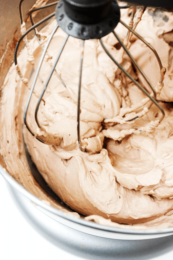 Chocolate Whipped Cream being whisked in a metal bowl of a stand mixer up close