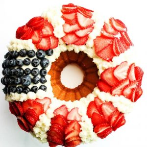 Red, White, & Blue Bundt Cake with Fresh Berries is a festive recipe with yellow cake topped with vanilla buttercream and fresh strawberries & blueberries.