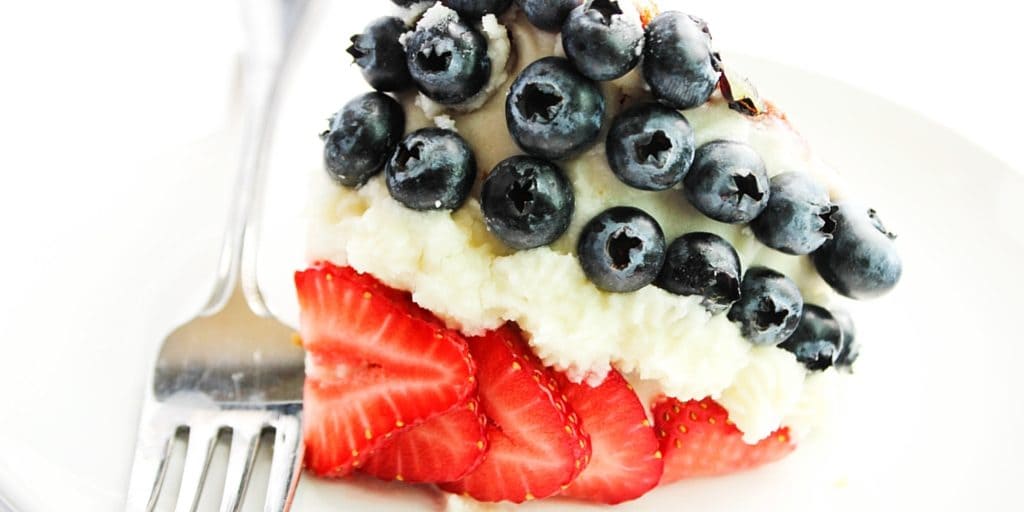 Red, White, & Blue Bundt Cake with Fresh Berries is a festive recipe with yellow cake topped with vanilla buttercream and fresh strawberries & blueberries.