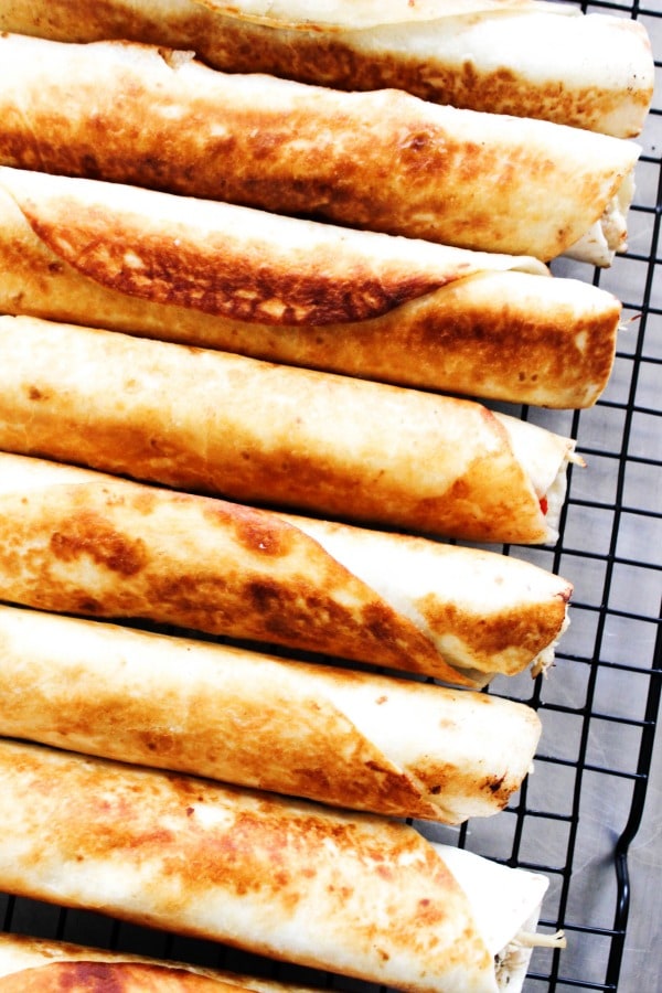 Slow Cooker Greek Chicken Taquitos is a twist on classic chicken taquitos. Made with fresh tomatoes, feta, and Greek dressing, this is so easy & delicious. 