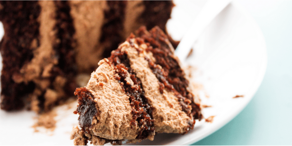 bite of chocolate cake on a fork laying next to a slice of cake on a plate