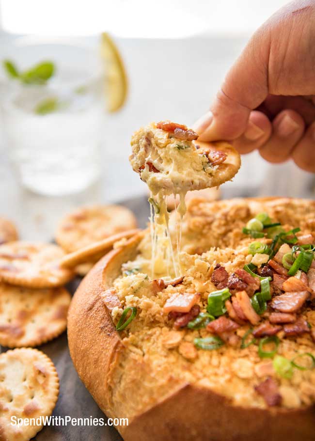 Warm Bacon Cheese Dip in bread bowl with crackers and scallions