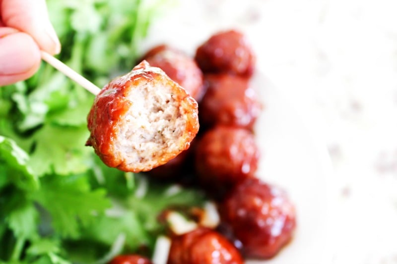 SWEET & TANGY BARBECUE MEATBALLS - Ready in 30-minutes and made with a few simple ingredients, they make appetizer or even as dinner a meatball subs. Sweet & Tangy Barbecue Meatball up close on a toothpick with meatballs and cilantro in background