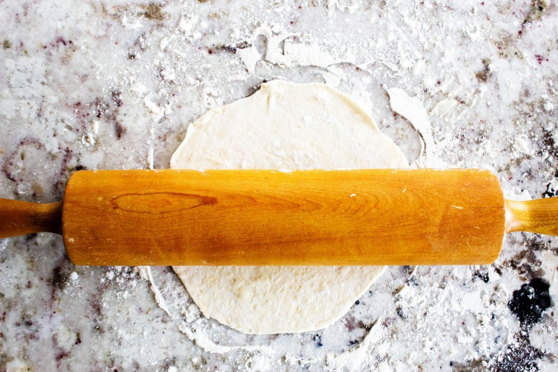 Best Ever Flour Tortillas are so easy & delicious that once you make these you'll never go back to store bought tortillas again. Flour Tortilla dough being rolled out on a floured countertop with a wooden rolling pin