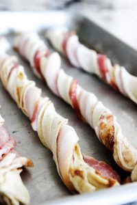 pastry dough twisted with bacon on baking sheet unbaked