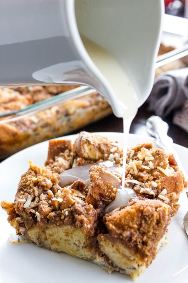 Overnight Coconut Cinnamon Pecan French Toast Casserole - Elevate your morning breakfast with this deliciously easy, make-ahead-breakfast casserole. photo showing icing being poured onto a slice of Overnight Coconut Cinnamon Pecan French Toast Casserole on a plate