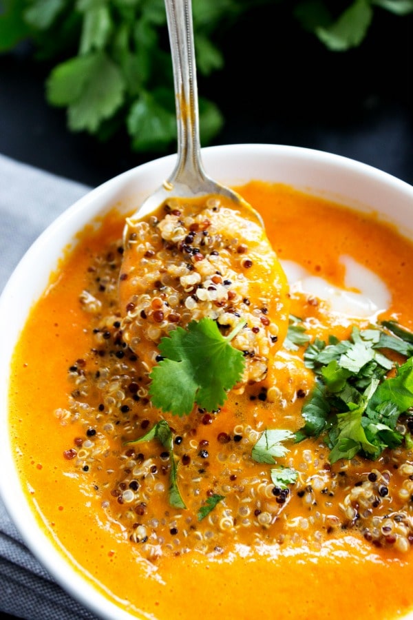 Thai Curry Red Pepper Quinoa Soup is an easy 30-minute meal made with red curry, coconut milk and quinoa. Skip take-out and make this healthy twist instead. top down photo of a spoonful of Thai Curry Red Pepper Quinoa Soup being spooned from a bowl