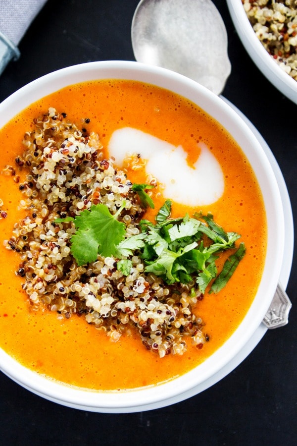 Thai Curry Red Pepper Quinoa Soup is an easy 30-minute meal made with red curry, coconut milk and quinoa. Skip take-out and make this healthy twist instead. top down photo of Thai Curry Red Pepper Quinoa Soup in a white bowl, with big soup spoon on table