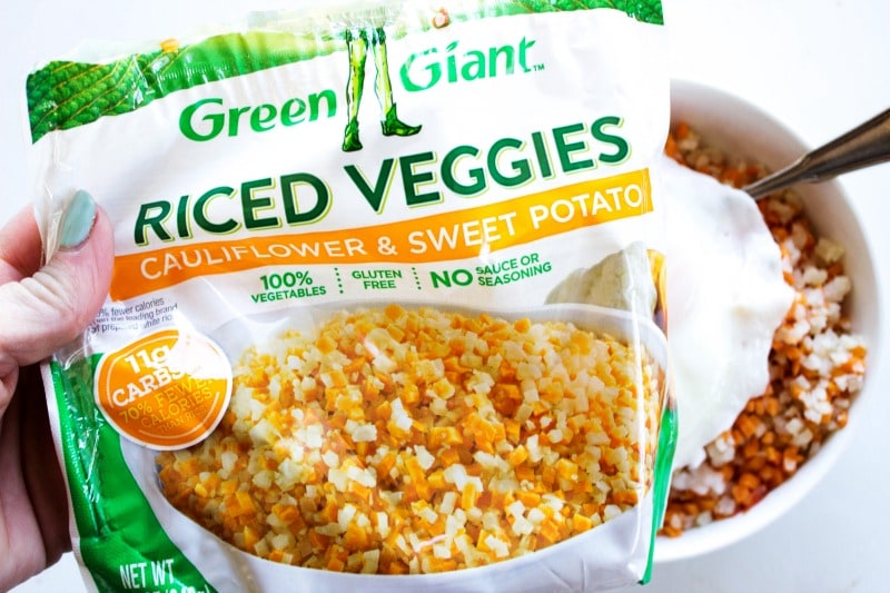 These Sweet Ginger Teriyaki Chicken Bowls made in just 30 minutes, are a healthy, filling, yet delicious dinner that will have you skipping take-out. photo of a bag of riced veggies, cauliflower and sweet potato, over a bow of the veggies