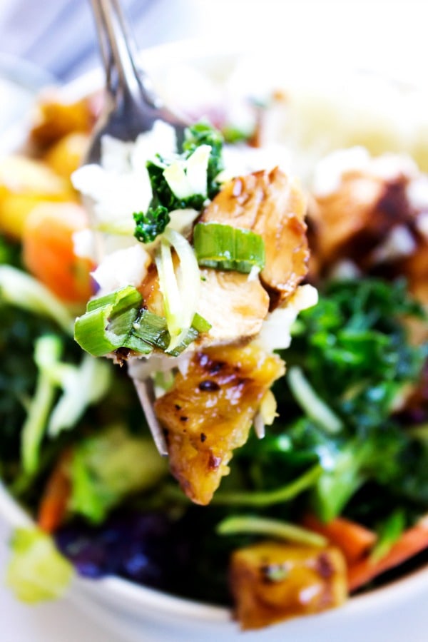 These Sweet Ginger Teriyaki Chicken Bowls made in just 30 minutes, are a healthy, filling, yet delicious dinner that will have you skipping take-out. up close of fork with a bite of sweet ginger teriyaki chicken on it, over a Sweet Ginger Teriyaki Chicken Bowl