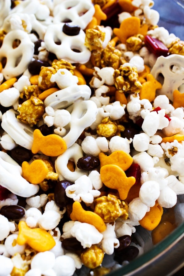 Horsetooth Trail Mix is an easy snack that you can mix together in just a few minutes. Perfect for playing a game with the kids or hiking with the family. photo of Horsetooth Trail Mix in a glass bowl. popcorn, goldfish, yogurt pretzels, caramel corn, licorice pieces and chocolate covered raisins