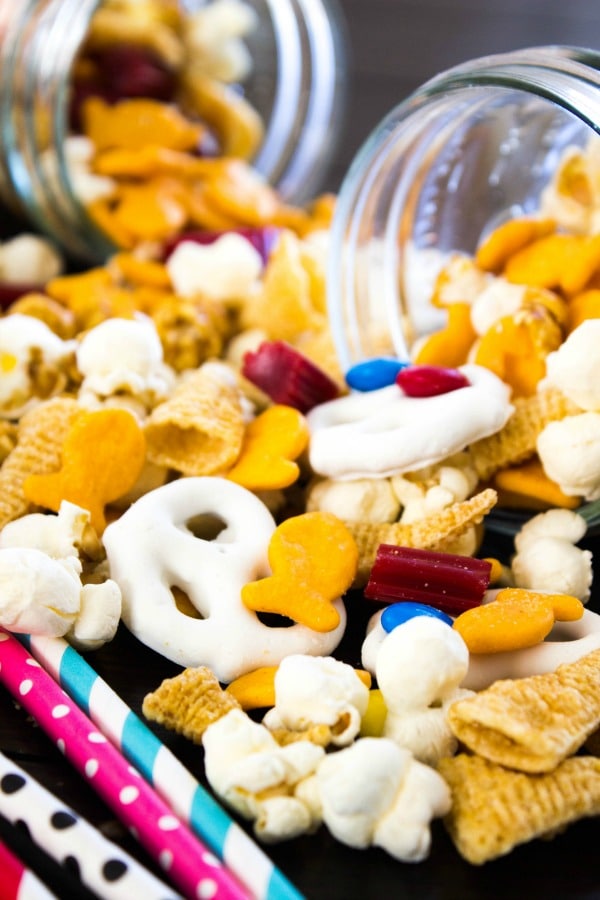 close up of trail mix spilling out of glass mason jars onto table