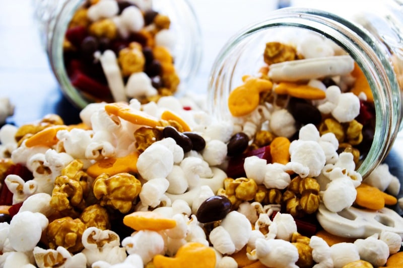 Horsetooth Trail Mix is an easy snack that you can mix together in just a few minutes. Perfect for playing a game with the kids or hiking with the family. photo showing horsetooth trail mix spilling out of two mason jars on their sides, in a pile on a table