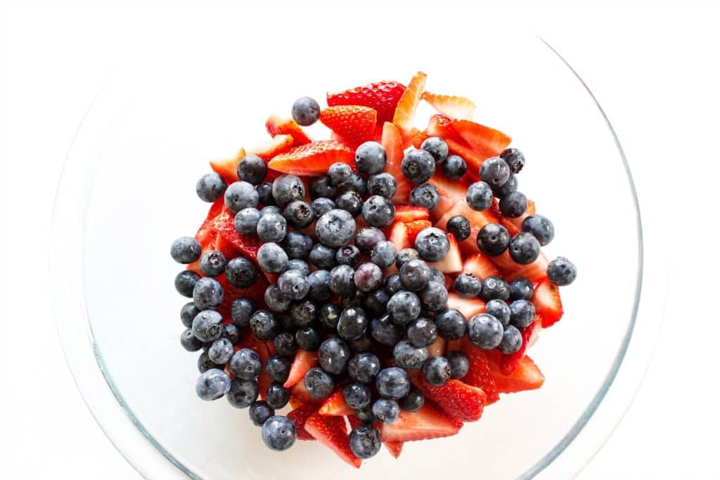 overhead shot of glass bowl with strawberries and blueberries