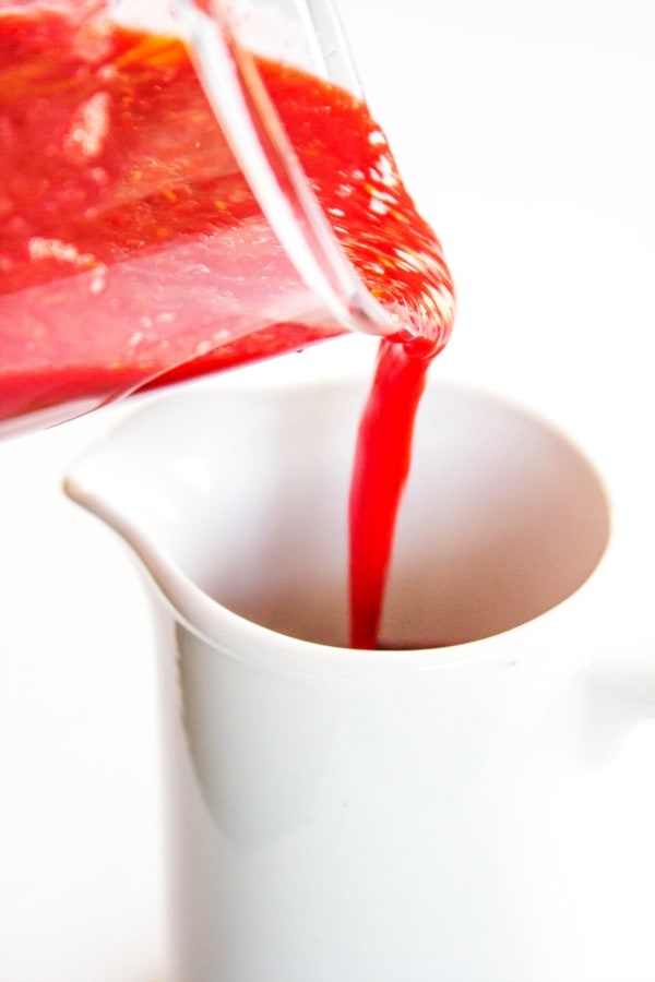 RASPBERRY PEACH SAUCE - a classic summer combination of peaches and raspberries made into a gorgeous sauce that will brighten any dish. From dessert to breakfast you will want to pour this sauce on it all. jar of raspberry peach sauce being poured into container