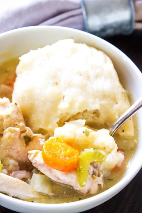 photo of chicken and dumplings oup in a white bowl with a spoon