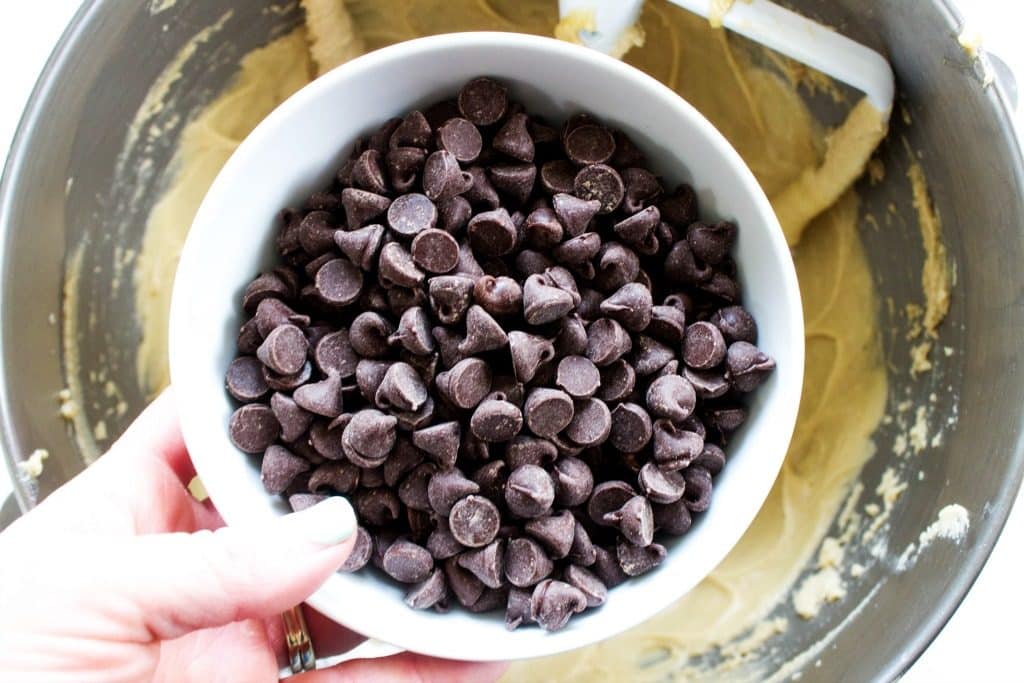 overhead shot of chocolate chips over bowl of cookie dough
