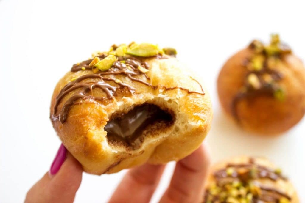 Nutella donut with pistachios and Nutella drizzle on top with bite out of it